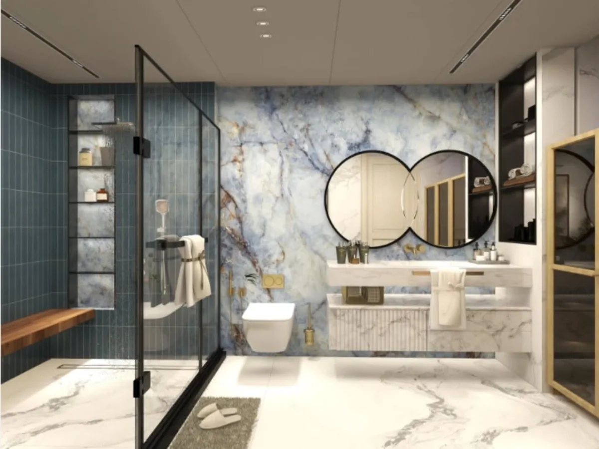 Desain kamar mandi elegan dengan dinding aksen marmer biru oniks yang artistik, cermin ganda berbentuk lingkaran yang saling tumpang tindih, meja wastafel marmer gantung, dan partisi shower kaca dengan bingkai hitam minimalis.