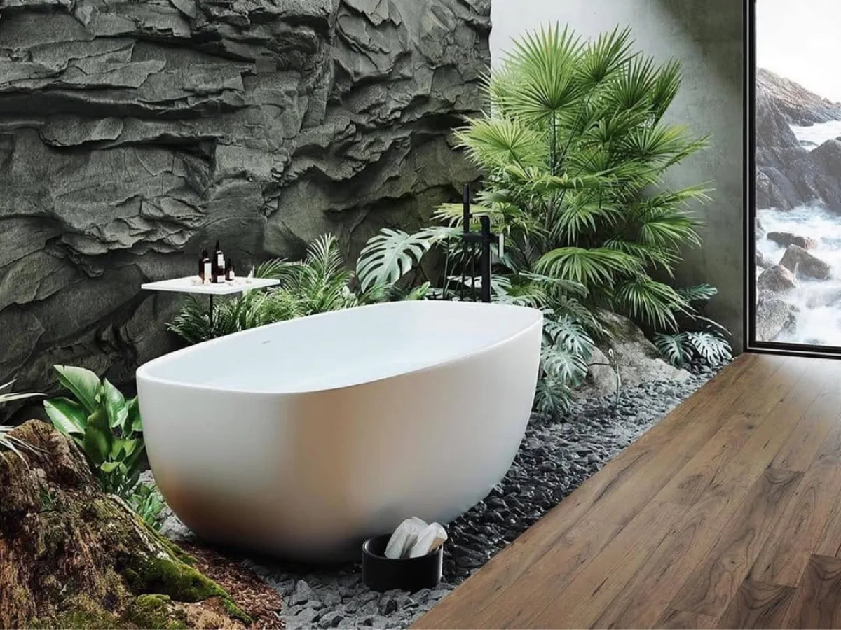 Kamar mandi modern bernuansa alam dengan bathtub putih, dinding batu bertekstur, lantai kayu, dan tanaman hijau di dalam ruangan.